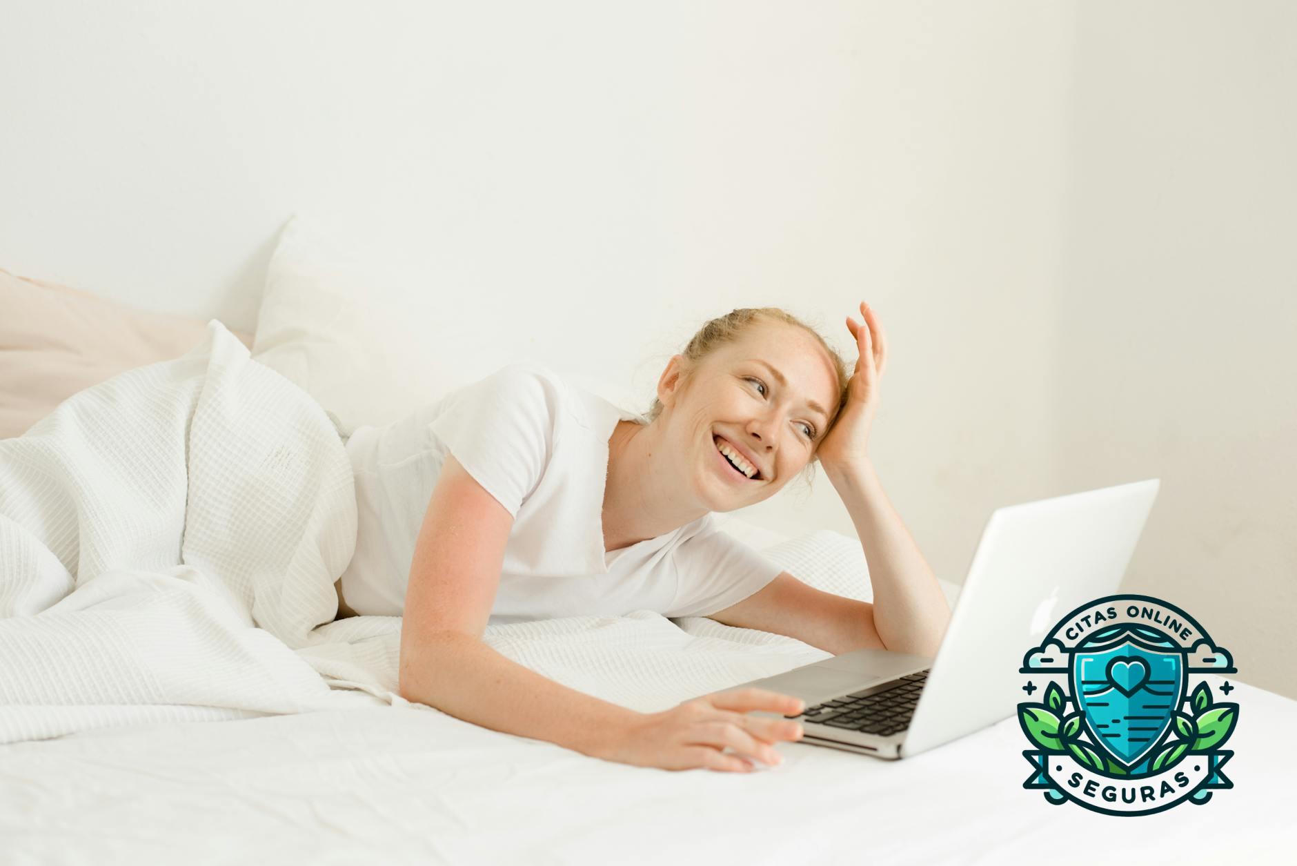 smiling woman lying down with laptop in bed
